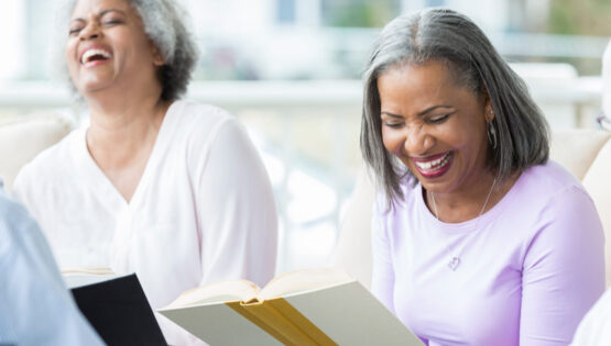 Cheerful group of seniors study the Bible together in their retirement community. A woman is reading from her Bible