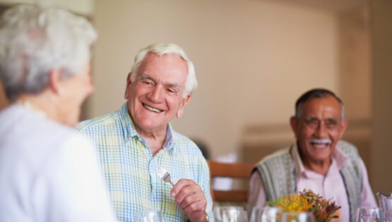 A group of seniors enjoying lunch together in the dining hall of a nursing home