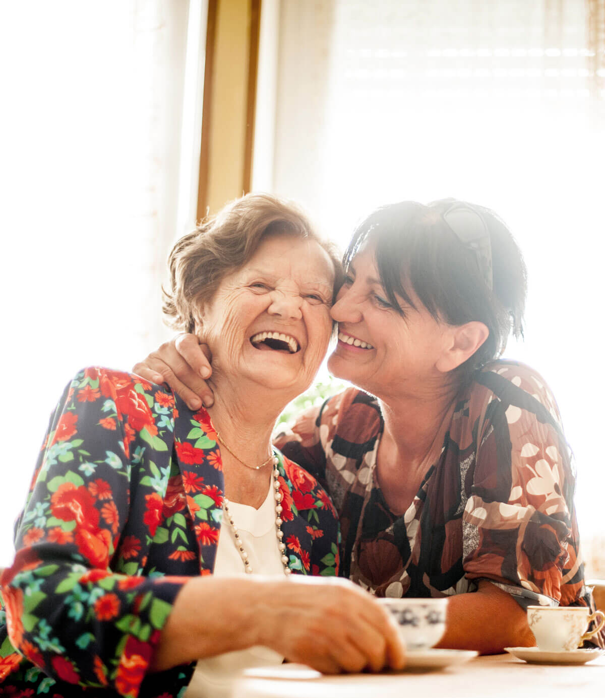 senior and adult child drinking tea and laughing | The Hampton at Meadows Place senior and adult child drinking tea and laughing
