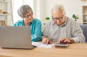 Seniors using a calculator and a laptop