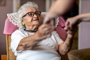 A person holding an older woman's hands