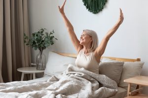 Older woman stretching on her bed joyfully