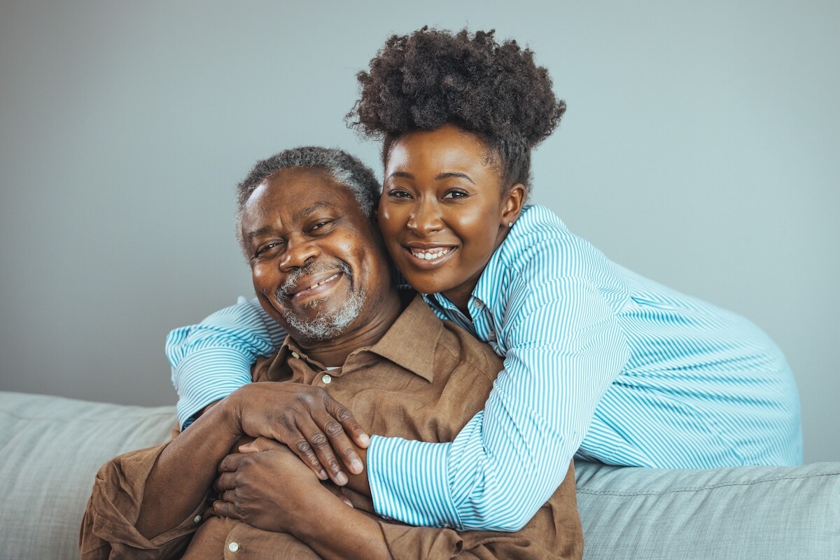 senior with daughter hugging happy | The Hampton at Meadows Place Smiling adult woman with her elderly parent