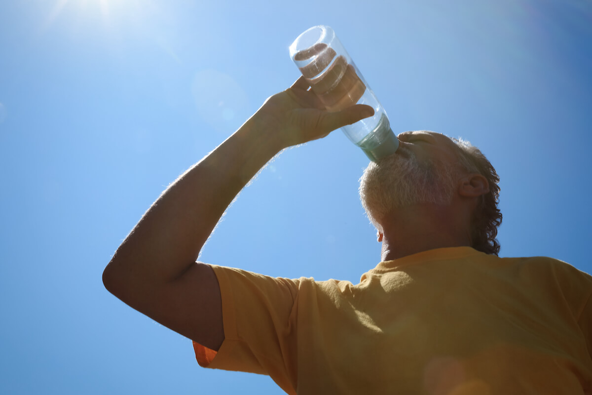 Older adult drinking water under the summer sun