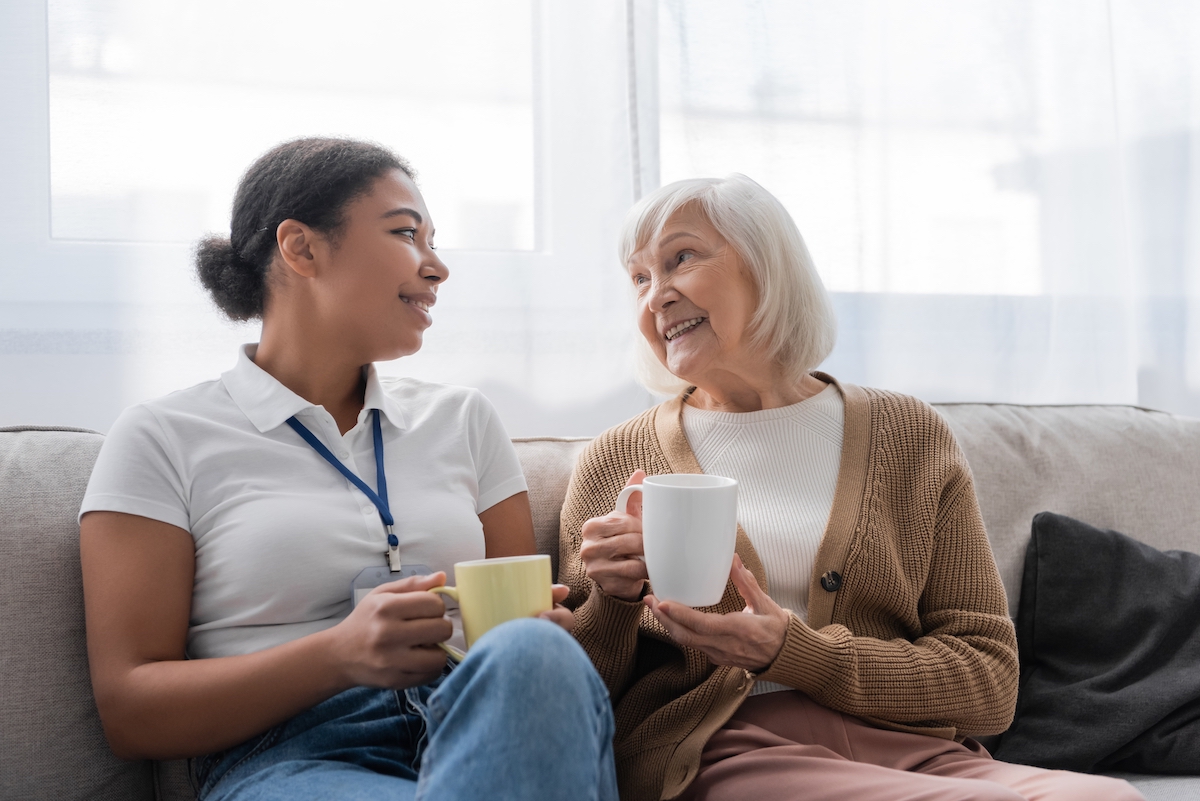 HappyMultiracialSocialWorkerHavingTeaAndChattingWithSenior | The Hampton at Meadows Place
