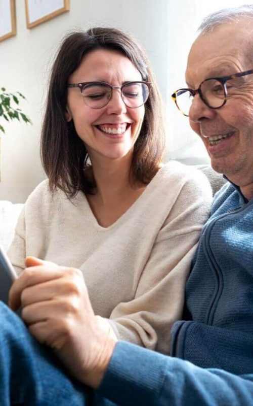 adult child and older adult looking at tablet cost of senior living